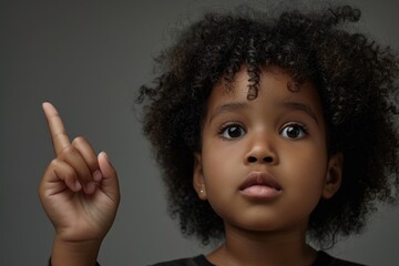 A young girl pointing with curiosity. Ideal for educational materials