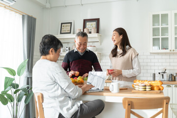 young daughter look to old mother cook in kitchen.Beautiful female enjoy spend leisure time and hugging senior elderly mom peel mango on table in home.Asian lovely family,Activity relationship concept