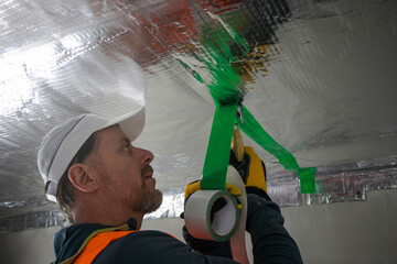 the construction worker uses aluminum tape and they had a roller for vapor barrier joints on the...