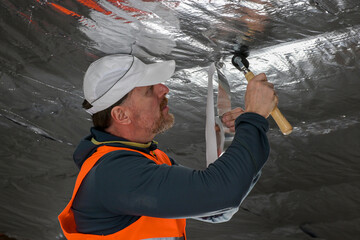 the construction worker uses aluminum tape and they had a roller for vapor barrier joints on the...