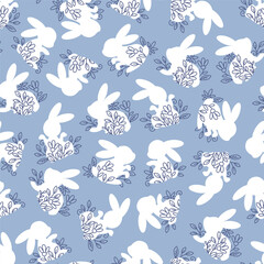 Silhouettes of Easter bunnies with flowers in a blue seamless pattern