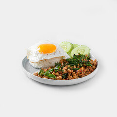 Stir-fried minced pork with basil and fried egg in a white plate on a white background