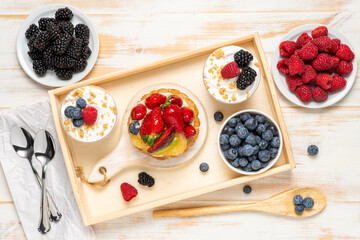 Sweet desserts with fresh berries on wooden background.