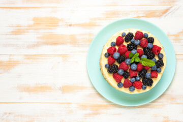Homemade cake with fresh berries on wooden background.