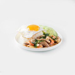 Stir-fried seafood with basil and fried egg in a white plate on a white background