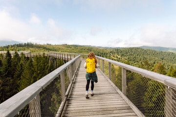 Young woman stands on a wooden bridge on the nature background. Travel, Freedom, active lifestyle concept. 