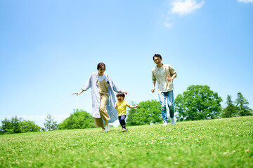 緑の丘で遊びまわる家族