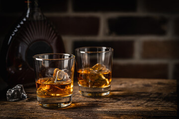 Whiskey with ice in glasses and bottle, dark background, copy space