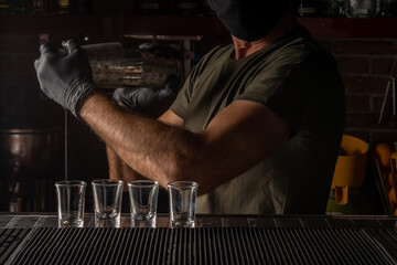 Barman in the bar shaking and mixing alcohol cocktail. Summer party background.
