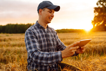 Smart farming and digital agriculture. Farmer working with Tablet on wheat field.