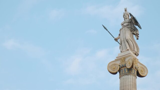 Statue of Athena on marble column from the Academy of Athens, Greece against blue sky. Popular landmark and travel destination