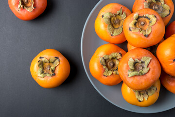 Delicious fresh persimmon fruits on black background.