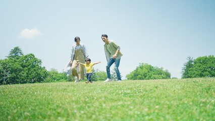 Obraz premium 緑の丘で遊びまわる家族