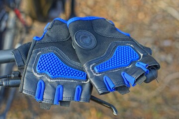 two new men's sports gloves with nylon black modern gloves lie on the iron handlebar of a mountain...