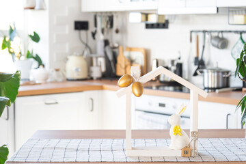 Key and tiny house of cozy home with Easter decor with rabbit and eggs on table of kitchen....