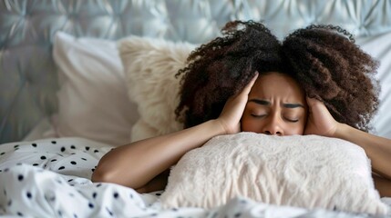 african american girl lying on bed with her head in her hands and eyes closed, headache, psychological problems and fatigue