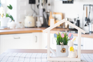 Key and tiny house of cozy home with Easter decor with rabbit and eggs on table of kitchen....