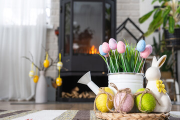 Easter decor near fireplace stove with fire and firewood. Cozy home hearth in interior with potted plans, colorful easter eggs, easter bunny and bouquet. Spring in a country house - Powered by Adobe