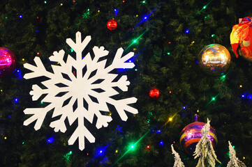 A large white snowflake on a dark background with flickering colored lights. Christmas street decor.