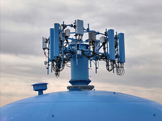 Cell phone antenna array mounted on top of a water tower close up - obrazy, fototapety, plakaty