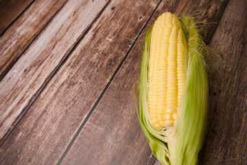 Fresh corn on the cob over wooden background Top view