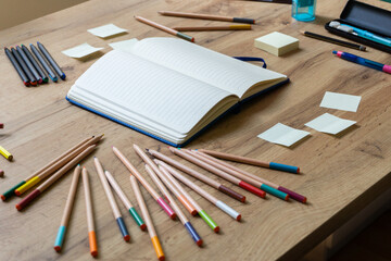 School accessories on wooden desk and notebook in the middle. Back to school concept. The beginning of the school season. Angle view