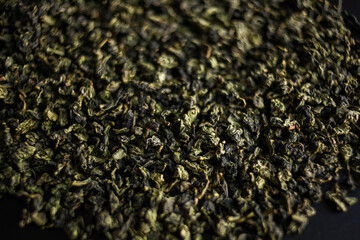 Green tea leaves form a pattern on black flooring