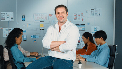 Portrait of professional businessman with arm crossed standing and looking at camera. Successful business people smiling to camera while business group discussion about marketing plan. Manipulator.