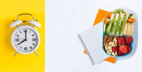 School lunchbox and white alarm clock on the yellow and white background. Top view. Copy space.