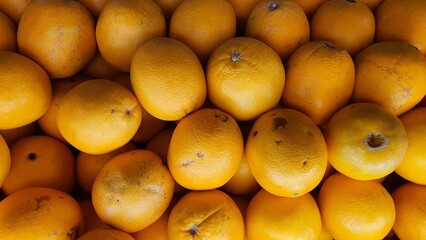 Close up pile of tasty fresh oranges sold at the market as a background.