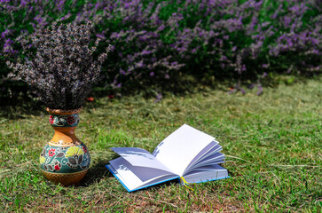 White open book lying on green lawn next to lavender field