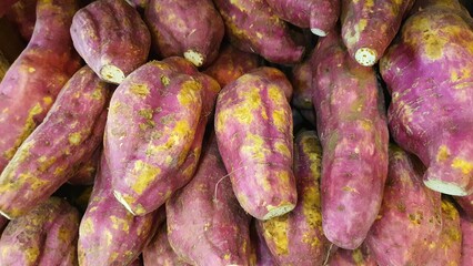 Close up pile of fresh sweet potatoes sold at the market as a background.	
