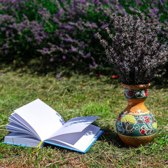 White open book lying on green lawn next to lavender field