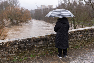 Watching the flooding of the River with his umbrella. Medieval Magadalena Bridge, Pamplona