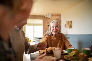 Happy senior woman having breakfast at home with family
