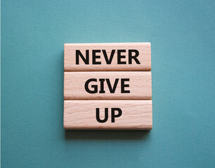 Never give up symbol. Concept words Never give up on wooden blocks. Beautiful grey green green background. Business and Never give up concept. Copy space.