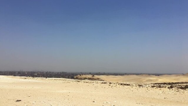 Pan of empty desert ending on 1/3 of a pyramid at Giza Necropolis.