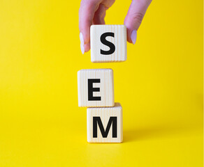 SEM - Search Engine Marketing symbol. Wooden cubes with words SEM. Businessman hand. Beautiful...