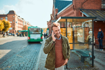 Mature man talking on his phone while waiting for a bus at the bus stop