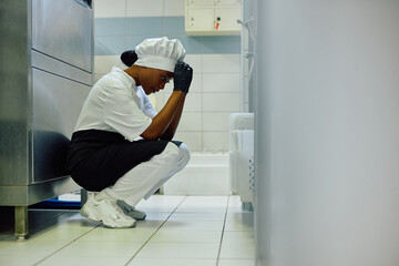 Black female cook feeling tired after shift in restaurant kitchen.