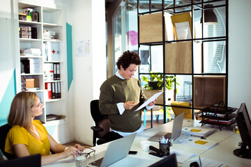 Young man holding document talking to colleagues in office