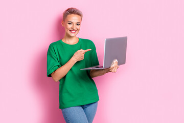 Portrait of charming nice girl indicate finger hand hold laptop empty space isolated on pink color...