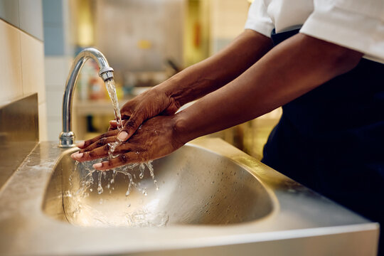 Close up of professional chef washing her hands while working in kitchen.