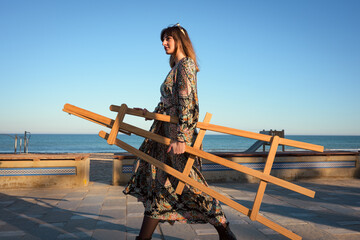 Woman Walking Down Sidewalk Carrying a Easel