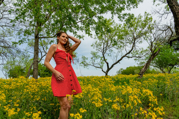 Naklejka na ściany i meble A Lovely Brunette Model Poses In A Field Of Yellow Flowers In A Texas Prarie