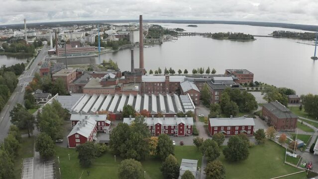 Factory is situated alongside a lake, with a bridge spanning across the water.
