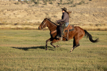 Cowgirl galloping horse across field