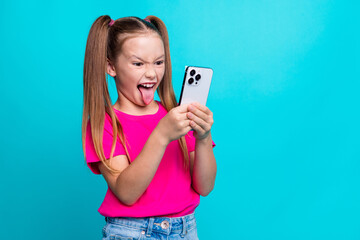 Photo of funky funny crazy schoolgirl with ponytails look at smartphone make selfie showing tongue...