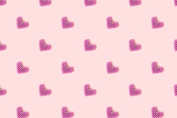 Handmade heart made of purple beads pattern on a pink background. Creativity concept.