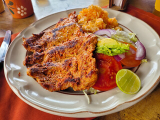 Juicy grilled enchilada steak served with a side of Mexican rice and fresh salad, food